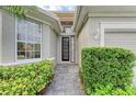 Front entry with black iron door and sidelights, and lush landscaping at 6710 Pebble Beach Way, Lakewood Ranch, FL 34202