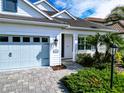 Front view of a white house with light blue garage door and landscaping at 13153 Steinhatchee Loop, Venice, FL 34293