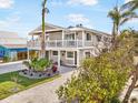 Two-story house with a white balcony, gray siding, and landscaped yard at 203 72Nd St, Holmes Beach, FL 34217