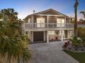 Two-story house with a white balcony, gray siding, and landscaped yard at 203 72Nd St, Holmes Beach, FL 34217