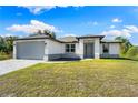 New single-story house with gray garage door and paver driveway at 2133 Selover Rd, North Port, FL 34287