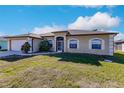 Tan house with white garage door and landscaping at 22419 Bette Ave, Port Charlotte, FL 33954