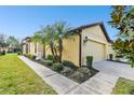 Side view of a yellow house with a single-car garage and lush landscaping at 314 Mystic Falls Dr, Apollo Beach, FL 33572