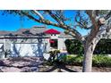 Gray house with red awnings, white garage door, and landscaping at 3465 Winding Oaks Dr # 33, Longboat Key, FL 34228