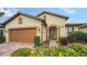 Tan house with orange garage door, lush landscaping, and a paved driveway at 5552 Eagle Creek Rd, Sarasota, FL 34238