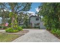 Two-story house with gray siding, paver driveway, and lush landscaping at 1702 Spoonbill Dr, Nokomis, FL 34275