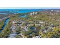 An aerial view showcasing a waterfront community and a homesite with mature trees at 32 Bayhead Ln, Osprey, FL 34229