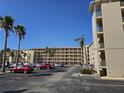 Multi-story condo complex with multiple balconies and parking lot featuring various parked cars and tropical foliage at 3682 Lake Bayshore Dr # K402, Bradenton, FL 34205