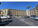 Multi-story condo complex with multiple balconies and parking lot featuring various parked cars on a sunny day at 3682 Lake Bayshore Dr # K402, Bradenton, FL 34205