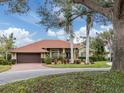 Tan house with red tile roof, palm trees, and a spacious front yard at 4539 Longspur Ln, Sarasota, FL 34238