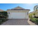 White garage door, paver driveway, and manicured landscaping at 7575 Quinto Dr, Sarasota, FL 34238