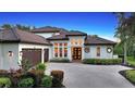 Two-story home with a tile roof, three-car garage, and a brick driveway at 8994 Wildlife Loop, Sarasota, FL 34238