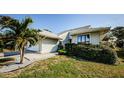 Light-grey house exterior with lush green hedges and palm tree at 1003 Lake Avoca Dr, Tarpon Springs, FL 34689