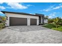 Modern home with two-car garage, gray paver driveway, and green lawn at 13377 Alocasia Ln, Port Charlotte, FL 33981