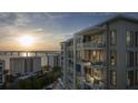 Modern condo exterior showcasing spacious balconies with seating areas and panoramic water views at sunset at 325 Golden Gate Pt # 802, Sarasota, FL 34236