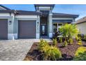 Front view of a two-story house with a gray exterior and a three-car garage at 18096 Home Run Dr, Venice, FL 34293