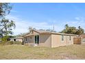 Back of tan house with sliding glass doors and a yard at 1518 Ewing Ave, Clearwater, FL 33756