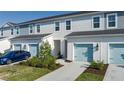 Three-unit townhome building with light gray siding, light blue garage doors, and landscaping at 8684 Canyon Creek Trl, Parrish, FL 34219