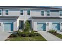 Three-unit townhome building with light gray siding, light blue garage doors, and landscaping at 8684 Canyon Creek Trl, Parrish, FL 34219