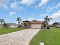 Tan house with a large paved driveway and palm trees at 25067 Palisade Rd, Punta Gorda, FL 33983