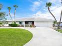 Ranch-style home with white exterior, attached garage, and manicured lawn at 548 Ketch Ln, Longboat Key, FL 34228
