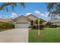 Tan house with white garage door, palm trees, and manicured lawn at 6726 Virginia Xing, University Park, FL 34201
