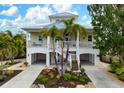 Two-story house with a light yellow exterior, palm trees, and a landscaped yard at 727 Holly Rd, Anna Maria, FL 34216