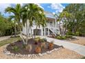 Two-story house with light-yellow siding, palm trees, and a landscaped front yard at 727 Holly Rd, Anna Maria, FL 34216