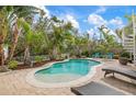 Freeform swimming pool with a patio, lounge chairs, and lush landscaping at 727 Holly Rd, Anna Maria, FL 34216