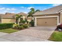 Home's exterior features a tan facade, two-car garage, and a brick-paved driveway at 12199 Sebring Ln, Venice, FL 34293