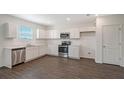 Modern kitchen with white cabinets, stainless steel appliances, and dark flooring at 13033 Cedar Elm Lane, Parrish, FL 34219