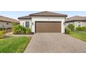 Front view of house with brown garage door and landscaping at 16127 Fortezza Dr, Bradenton, FL 34211