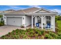 Charming one-story home with gray siding, covered porch, and neatly landscaped yard at 25042 Coquina Ridge Way, Englewood, FL 34223