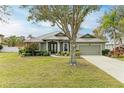 Single-story house featuring a metal roof, lush lawn, and mature trees at 304 147Th E St, Bradenton, FL 34212