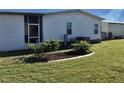 Rear view of manufactured home with small trees and lawn at 763 Lakeside Dr, North Port, FL 34287