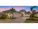 Beautiful home featuring white stucco, black window awnings, two-car garage, paved driveway and manicured landscaping at 8376 Sea Glass Ct, Sarasota, FL 34240
