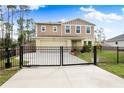 Two-story house with a tan exterior, black fence, and landscaped front yard at 1379 E Price Blvd, North Port, FL 34288