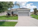 Charming one-story home with gray siding, solar panels, and a two-car garage. Features well-maintained landscaping and palm trees at 208 Cascade Bend Dr, Ruskin, FL 33570