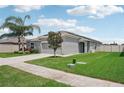 One-story home with gray siding, solar panels, and a two-car garage. Features a spacious yard with mature trees and lush grass at 208 Cascade Bend Dr, Ruskin, FL 33570