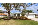 Single-story home with a white exterior, lush landscaping, and a two-car garage at 8303 Deerbrook Cir, Sarasota, FL 34238