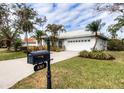 Landscaped home with a white exterior, two-car garage, and a mailbox at 8303 Deerbrook Cir, Sarasota, FL 34238