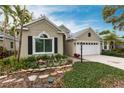 Tan house with white garage door, landscaping, and brick walkway at 96 Tall Trees Ct, Sarasota, FL 34232