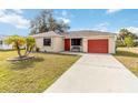 Single story home with red garage door and landscaped lawn at 20096 Tappan Zee Dr, Port Charlotte, FL 33952