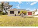 Single story home with red garage door and palm trees at 20096 Tappan Zee Dr, Port Charlotte, FL 33952