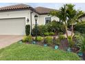 Landscaped front yard with palm trees, flowers, and a brick pathway at 5324 Popoli Way, Sarasota, FL 34238