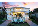 Coastal home with balconies and an American flag, enhanced by tropical landscaping and a colorful sunset at 718 Key Royale Dr, Holmes Beach, FL 34217