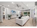 Open concept living room with white sectional sofa, hardwood floors, and access to a sunroom at 7946 Tybee Ct, University Park, FL 34201