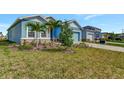 Landscaped front yard of a light blue house with palm trees at 16257 S Port Harbor Blvd, Port Charlotte, FL 33953