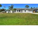 Newly renovated gray house with a lush green lawn and driveway at 4284 Watova Ave, North Port, FL 34286