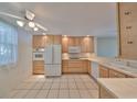 Kitchen with light wood cabinets, white appliances, and tile floor at 131 Pinehurst Dr # 131, Bradenton, FL 34210